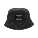 A Spiritbox Pigment Black Bucket Hat with a rectangular "TSUNA MISEA" patch on the front in white uppercase letters, featuring slightly textured fabric and a downward-sloping brim.
