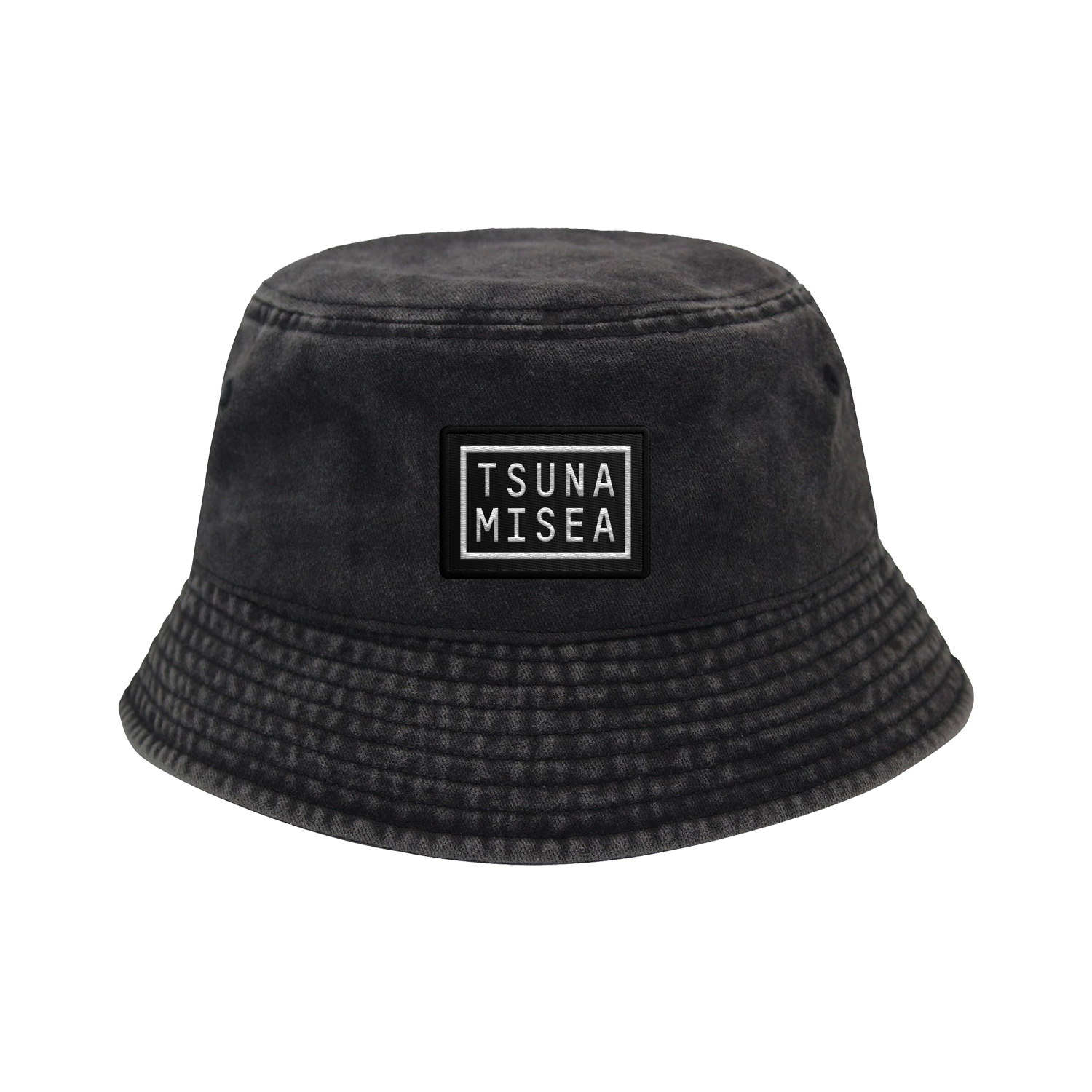 A Spiritbox Pigment Black Bucket Hat with a rectangular "TSUNA MISEA" patch on the front in white uppercase letters, featuring slightly textured fabric and a downward-sloping brim.