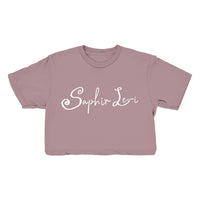 A mauve cropped t-shirt from Saphir Levi, featuring their name printed in white decorative script across the front—ideal for fans of stylish garments.