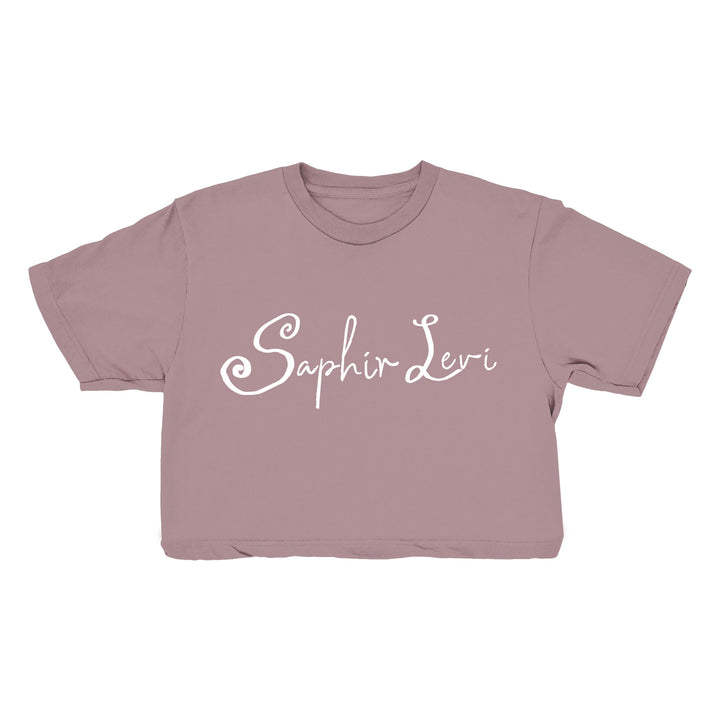 A mauve cropped t-shirt from Saphir Levi, featuring their name printed in white decorative script across the front—ideal for fans of stylish garments.