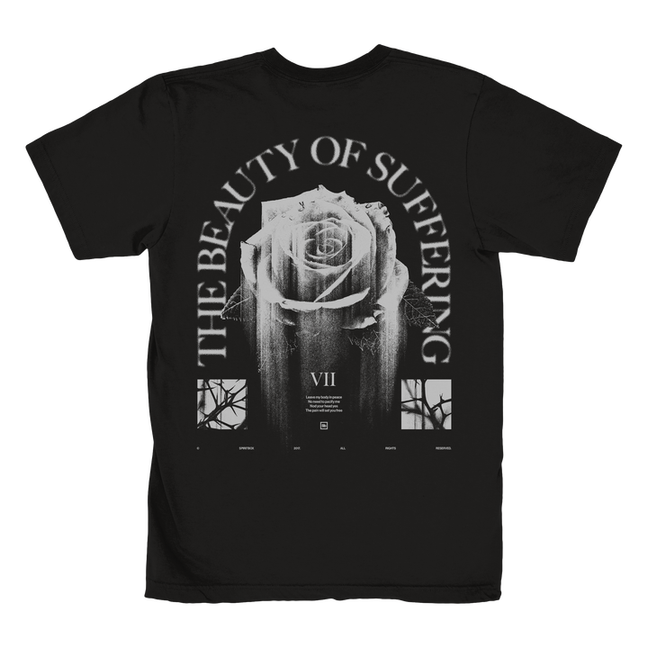 Black t-shirt by Spiritbox, made from 100% combed ring-spun cotton. Features a large white rose, “THE BEAUTY OF SUFFERING” text, three images beneath the rose, and Roman numeral VII. Fabric-laundered for softness.