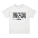 SIIICKBRAIN white T-shirt with a black-and-white print of a person sitting beside a cow in a stall, centered on the front. Printed on soft Comfort Colors fabric. Ships 4/3/26.