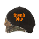 A black Thousand Below baseball cap with an orange gothic-style logo, barbed wire embroidery, and a bold diagonal camo print on the brim and side—a unique take on classic dad hats.