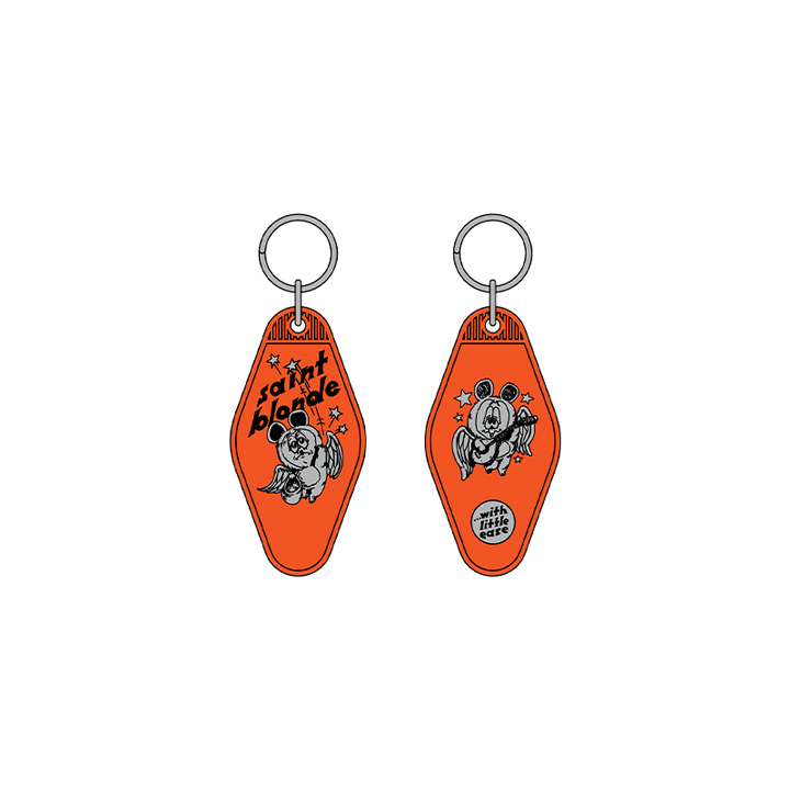 Two orange Saint Blonde motel-style keychains with metal rings feature cartoon bears and stars. One side reads "saint blonde," the other "United States of Texas." Available for presale; shipping starts 7/3/26!.