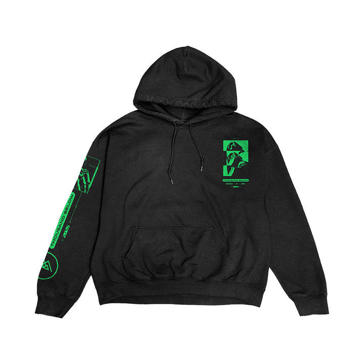 Thousand Below "Buried In Jade" black pullover hoodie with bright green graphics—abstract shapes, text, and a stylized face—on the left chest and right sleeve. Features a front pocket and drawstrings.