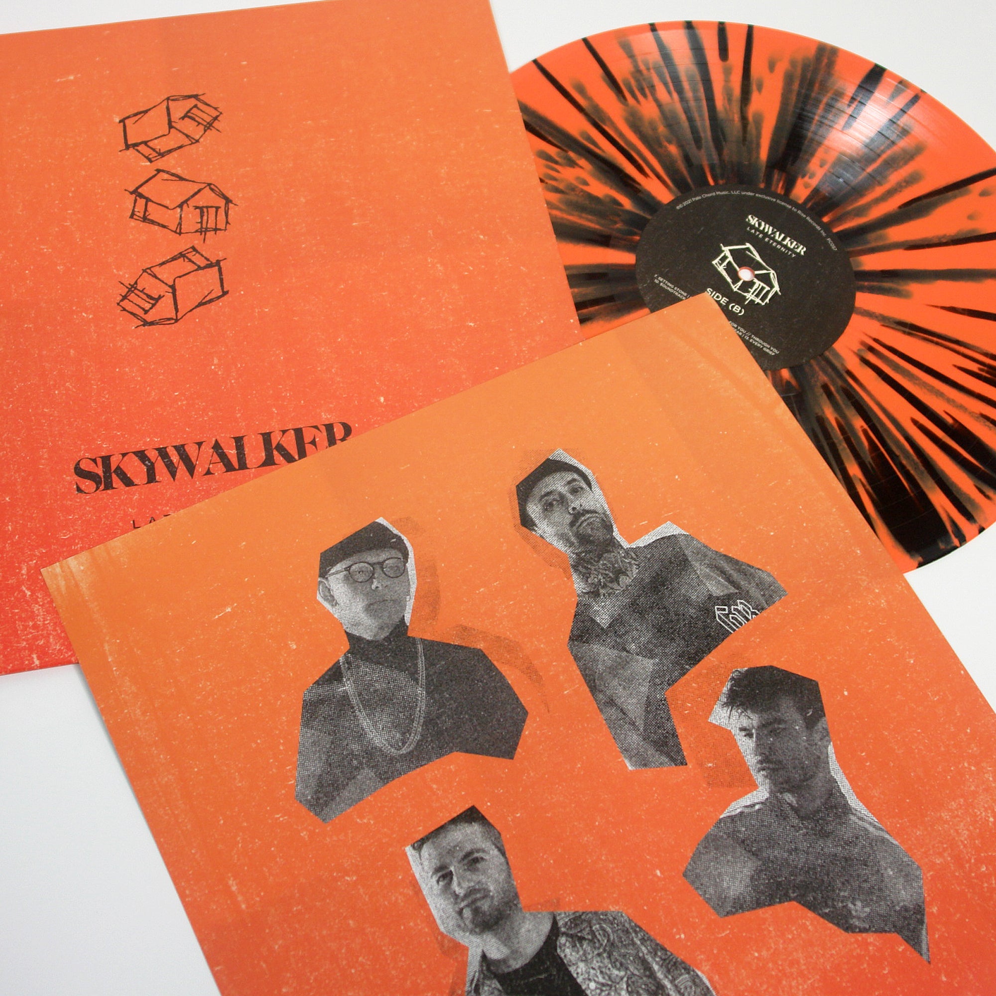 A Skywalker orange and black splatter vinyl partially out of its sleeve, next to an album cover with four black-and-white cutout portraits and SKYWALKER text on orange—featuring tracks like Ignis and No Leader.