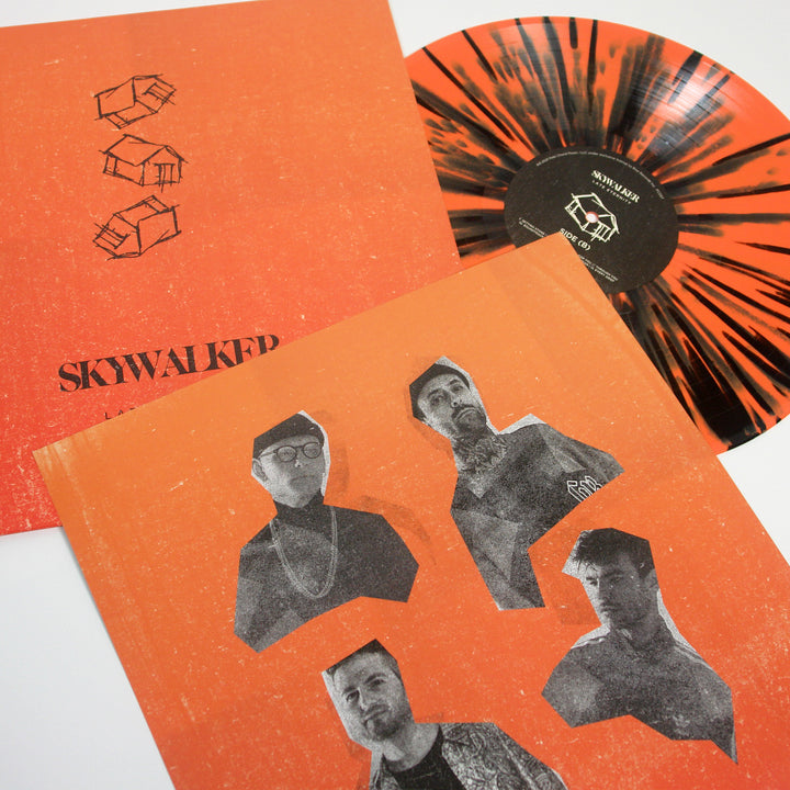 A Skywalker orange and black splatter vinyl partially out of its sleeve, next to an album cover with four black-and-white cutout portraits and SKYWALKER text on orange—featuring tracks like Ignis and No Leader.
